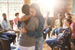 2 women hugging surrounded by a group