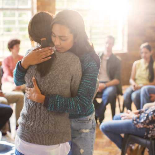 2 women hugging surrounded by a group